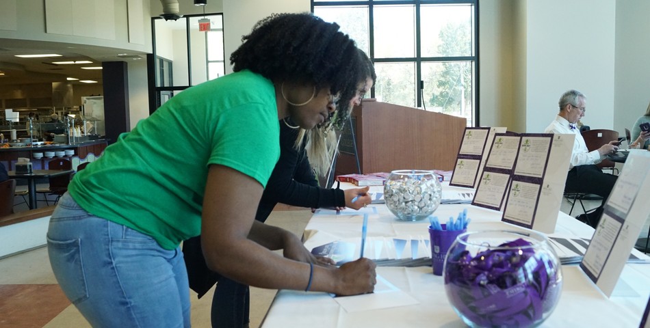 : Students sign up at the Give Day table in the cafeteria. 